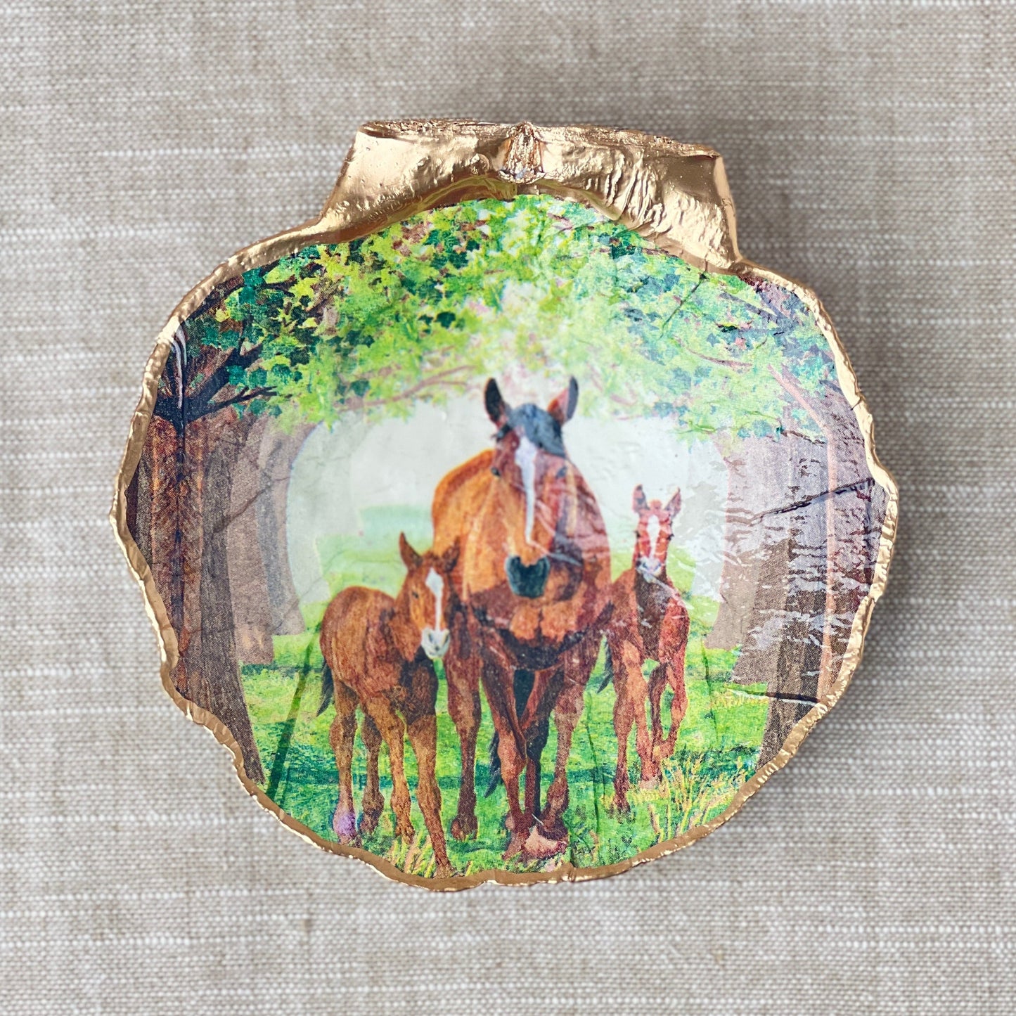 A scallop shell ring dish with a hand-decorated horse design, displayed on a beige background.
