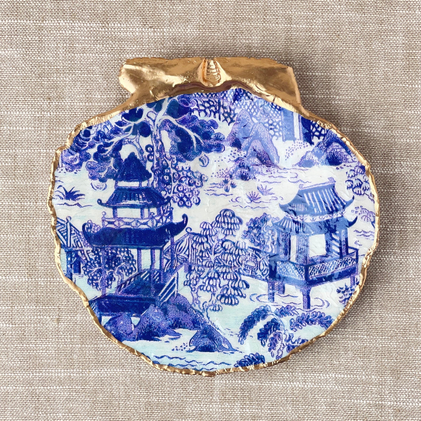 Decorative plate with blue and white design on a beige fabric background