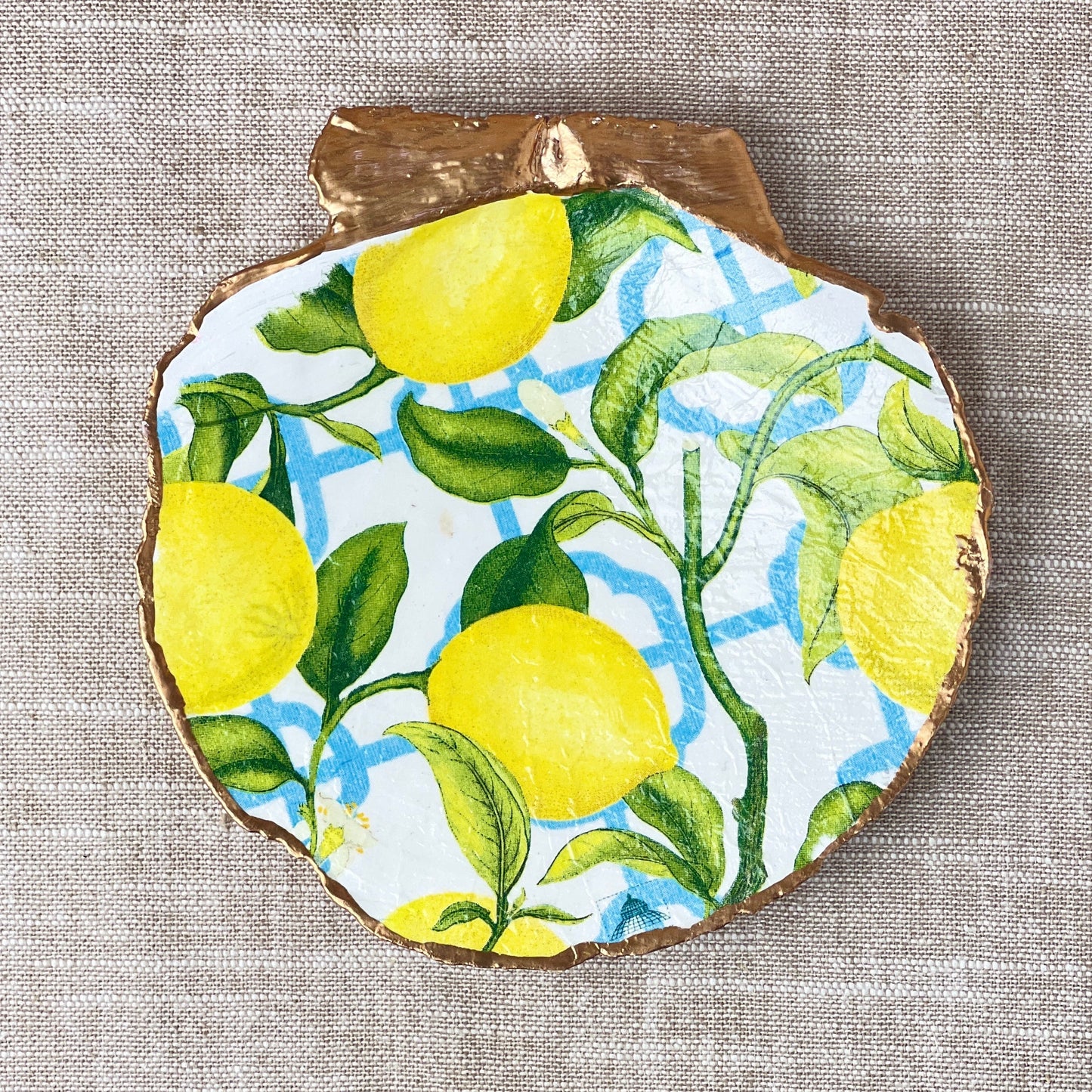A scallop shell with a French Lemon design used as a ring dish, displayed on a table with a neutral linen cloth.
