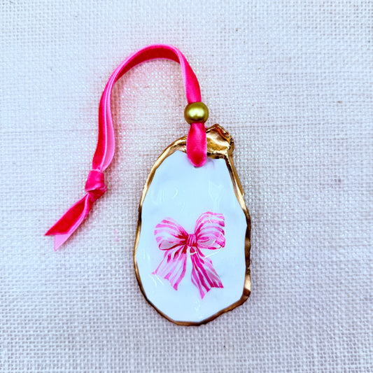 Decorative oyster christmas ornament with pink bow design on a white background