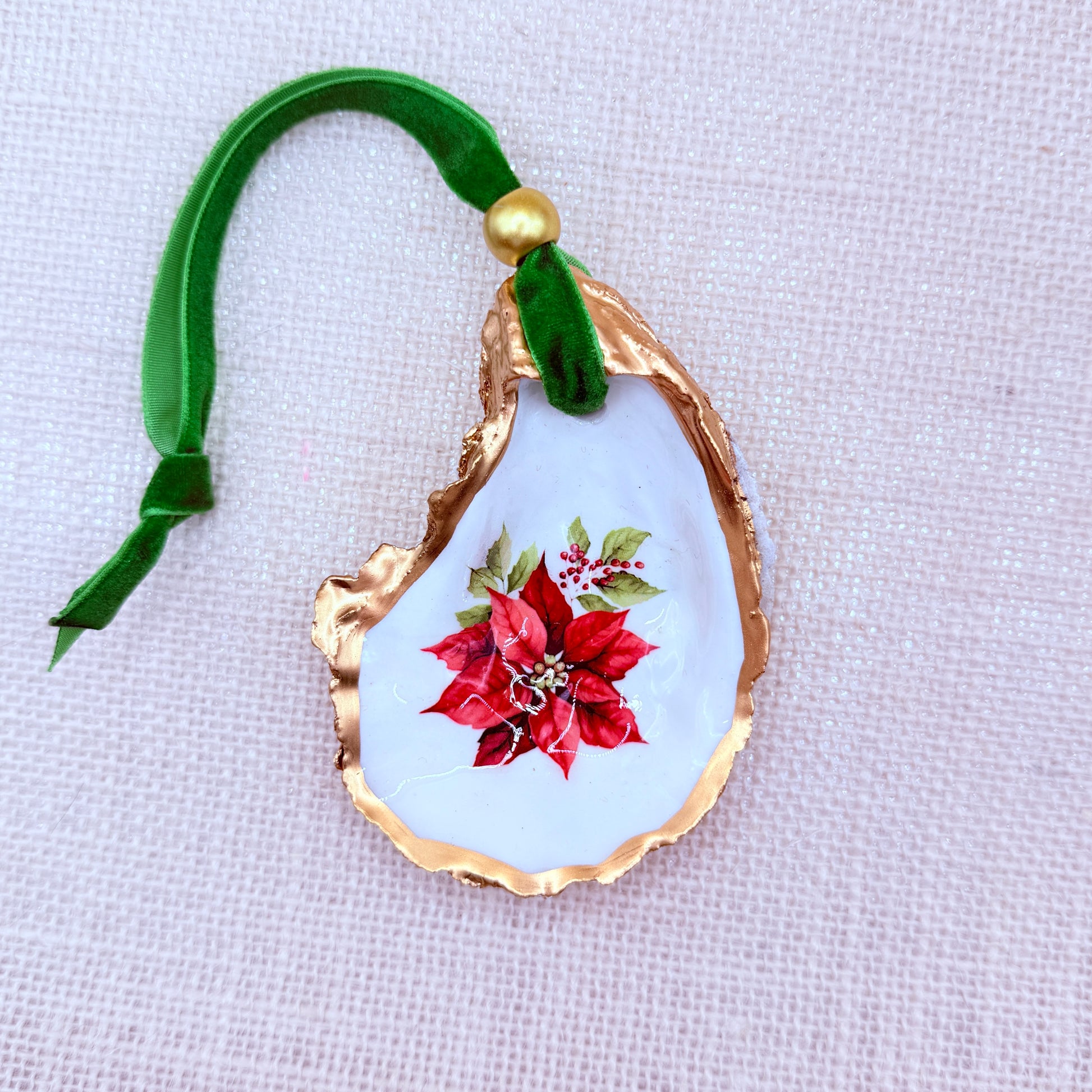 Decorative oyster ornament with poinsettia design on a white background