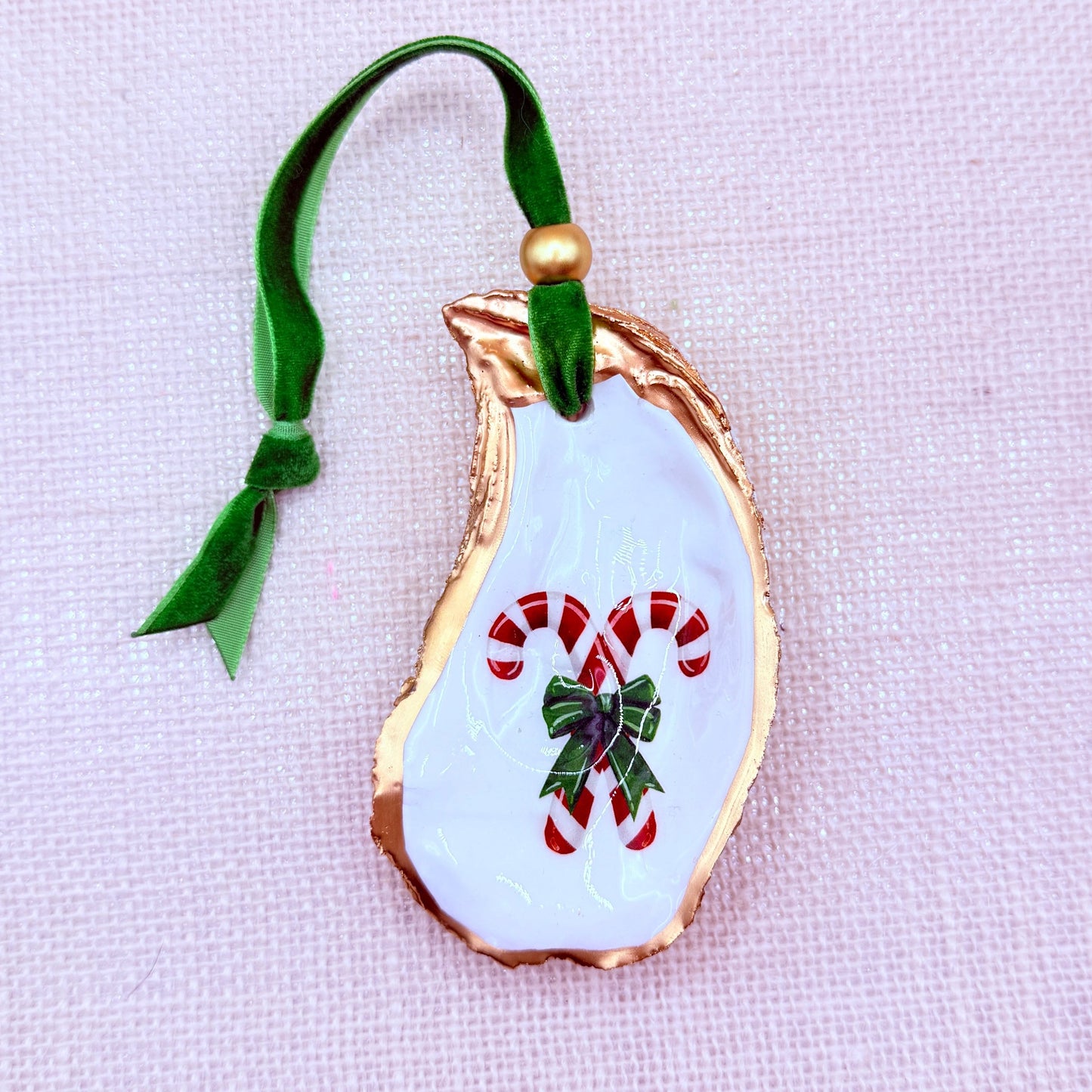 Decorative Christmas oyster ornament with candy canes and a bow on a light background