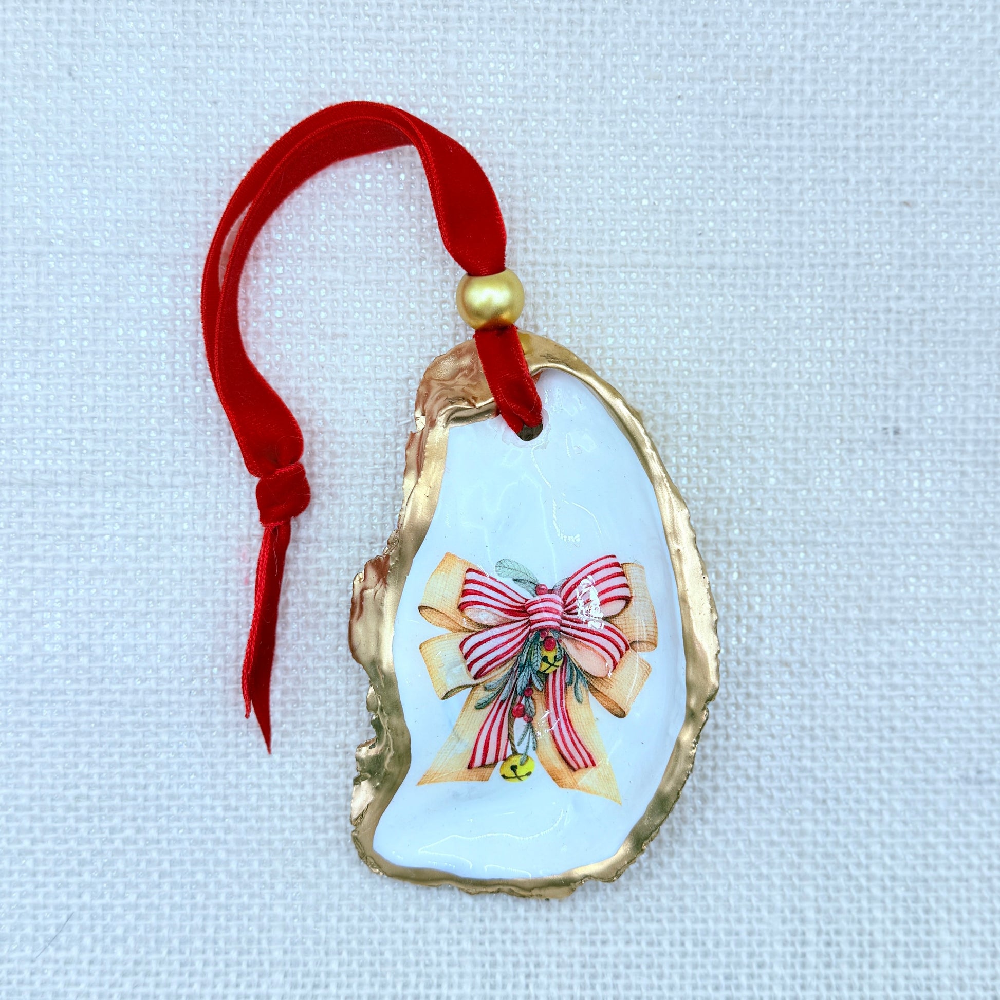 Decorative oyster ornament with a red ribbon on a light fabric background