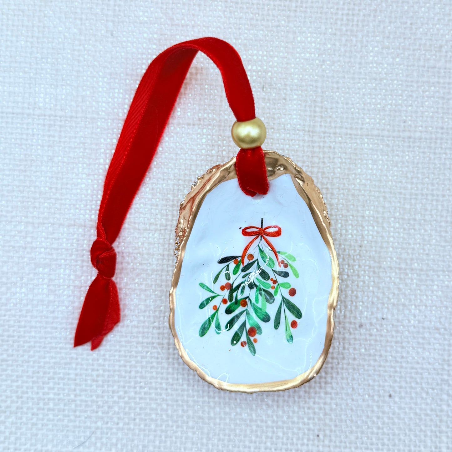 Decorative oyster shell ornament with mistletoe design on a light background