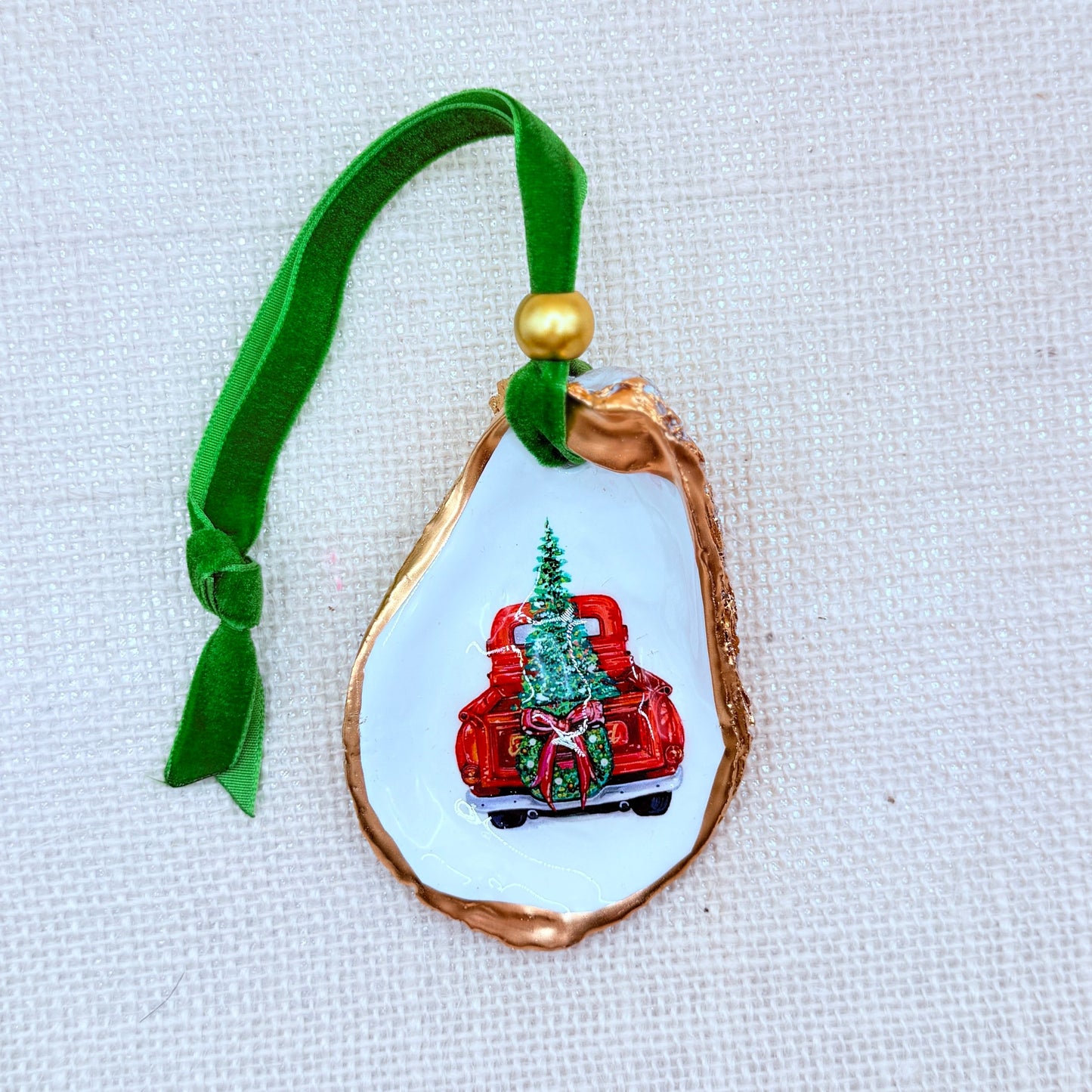 Decorative ornament with a truck and Christmas tree design on a white background.