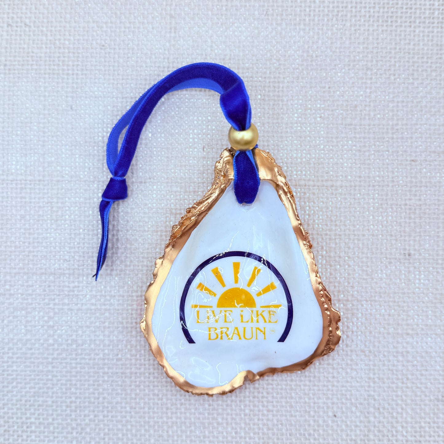 Decorative ornament with 'Live Like Braun' logo on a textured white background