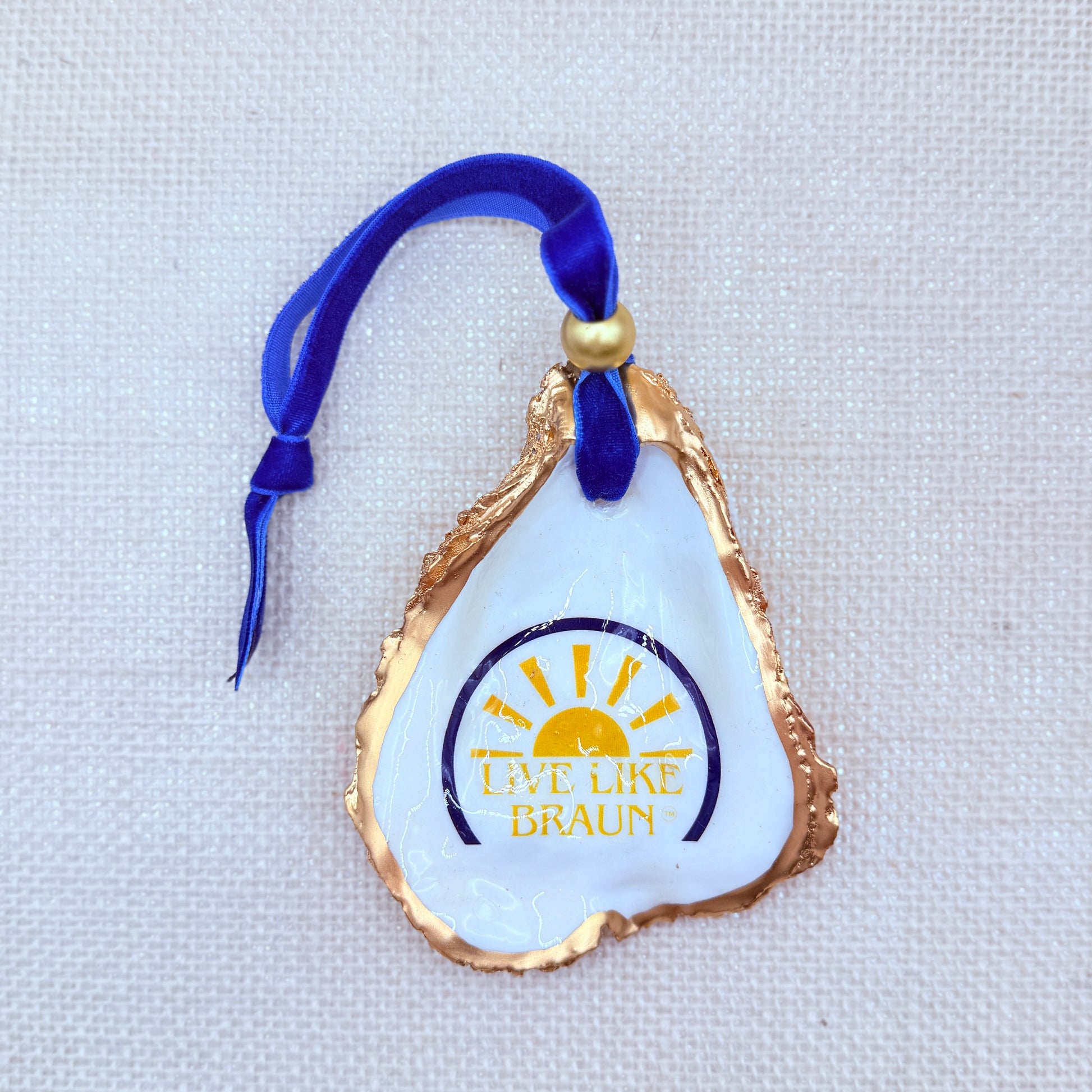 Decorative ornament with 'Live Like Braun' logo on a textured white background