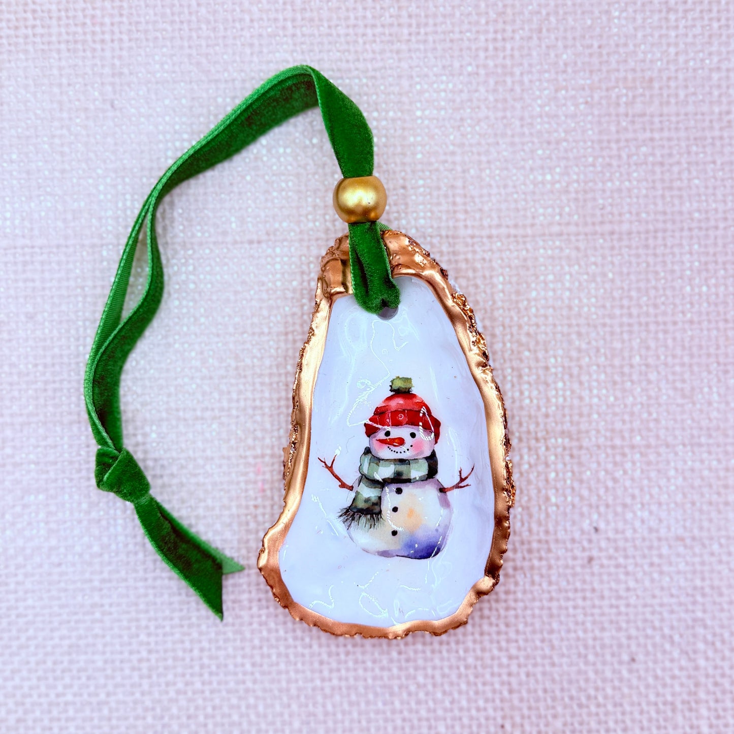 Decorative oyster ornament with a snowman design on a white background
