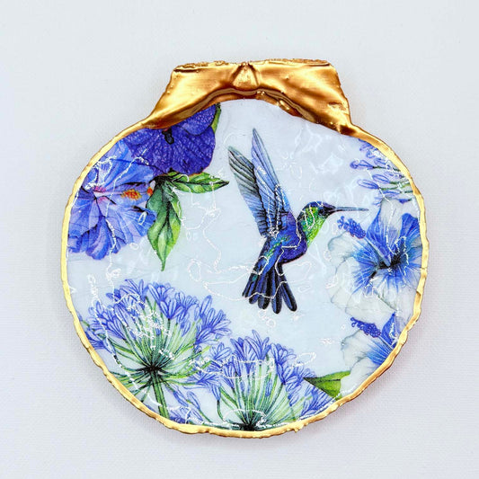 Decorative plate with a gold rim featuring a blue and green bird and floral design on a light gray background.