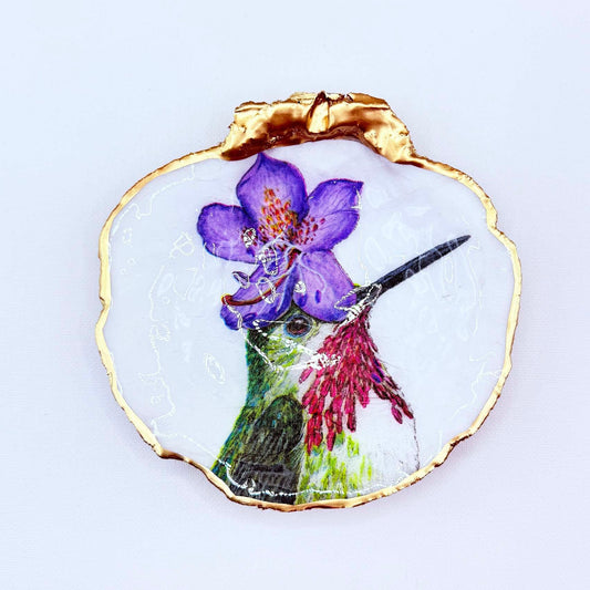 Humming bird with purple flower hat design on while background on scallop shell jewelry dish.