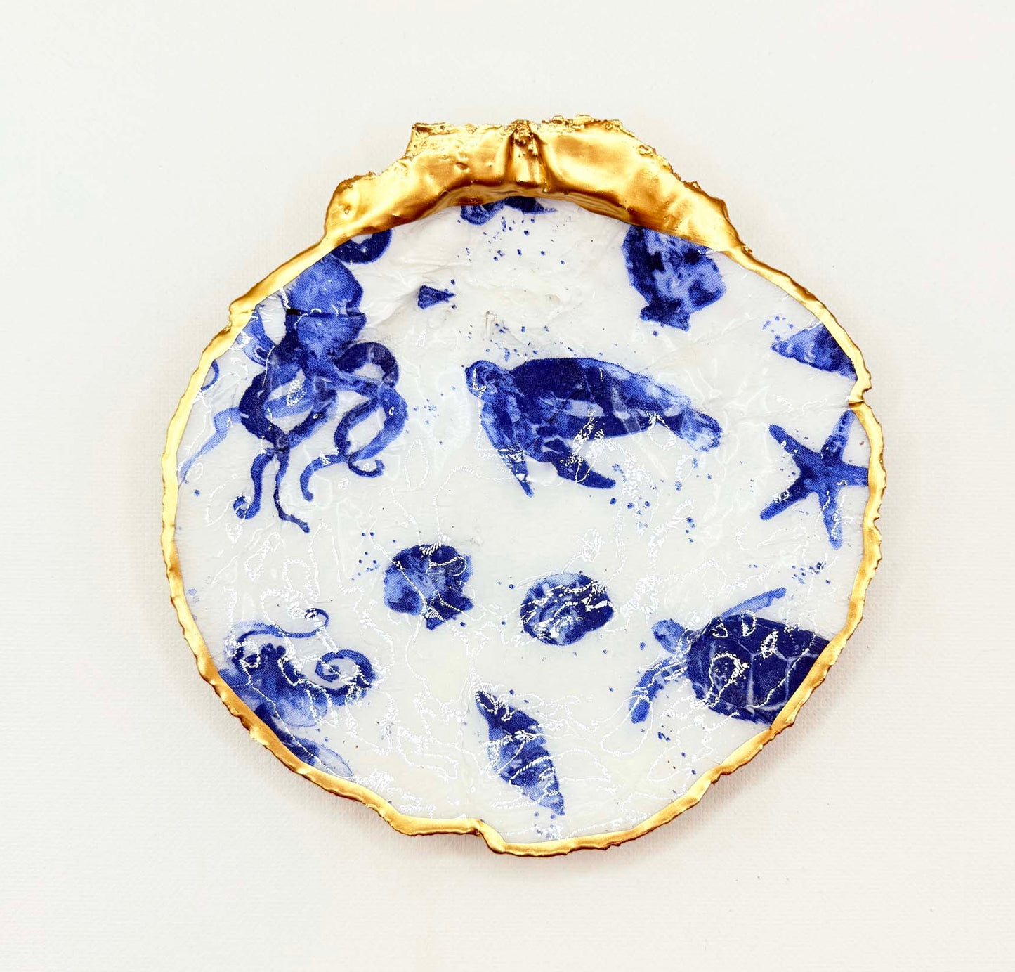 Decorative plate with blue sea-themed design and gold rim on a white background