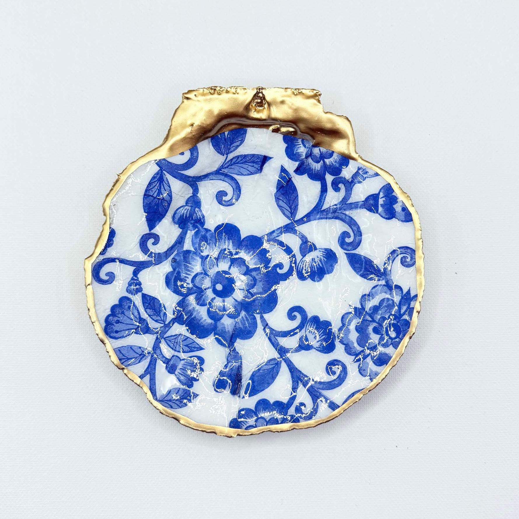 Decorative plate with blue floral design and gold rim on a light gray background