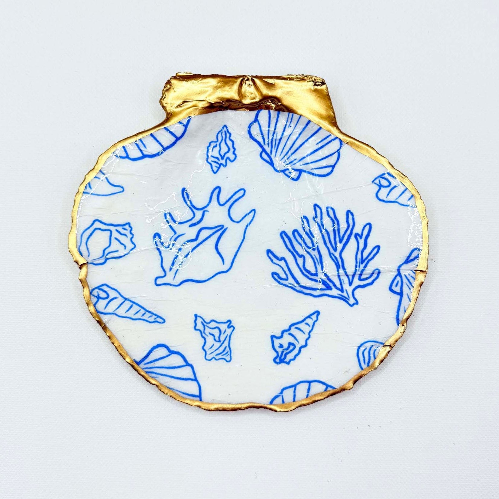 Decorative plate with gold rim and blue sea-themed shell patterns on a white background