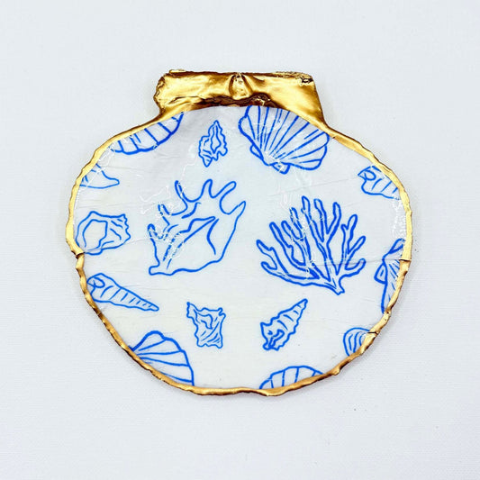 Decorative plate with gold rim and blue sea-themed shell patterns on a white background