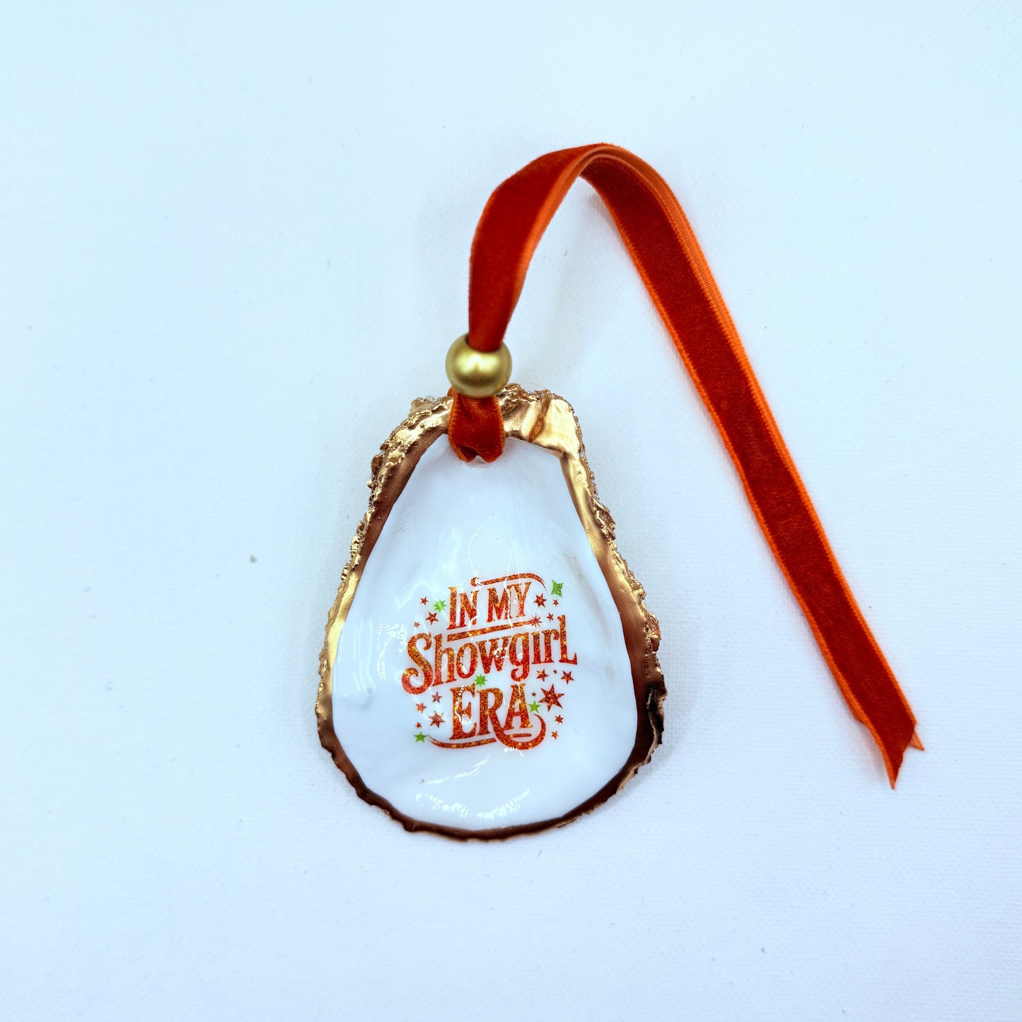Oyster ornament with 'In My Showgirl Era' text on a white background Orange hang tie