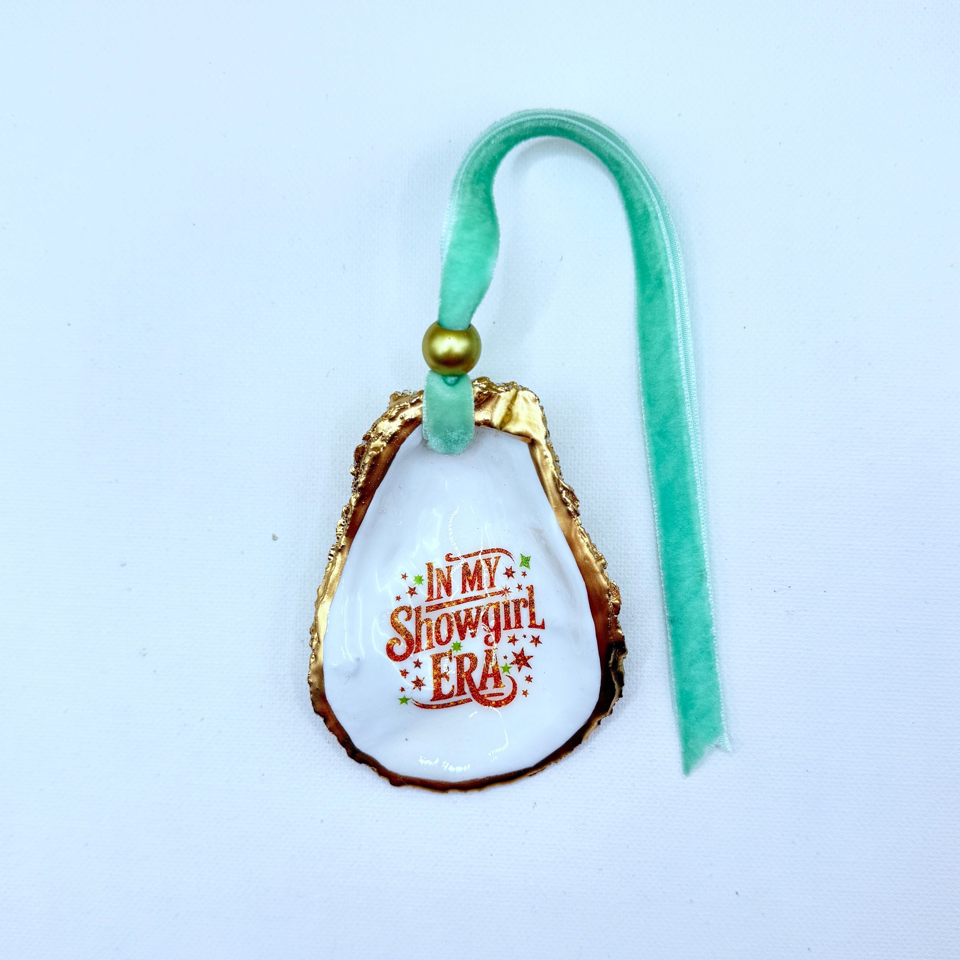Decorative oyster ornament with 'In My Showgirl Era' text on a white background