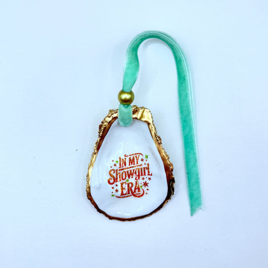 Decorative oyster ornament with 'In My Showgirl Era' text on a white background