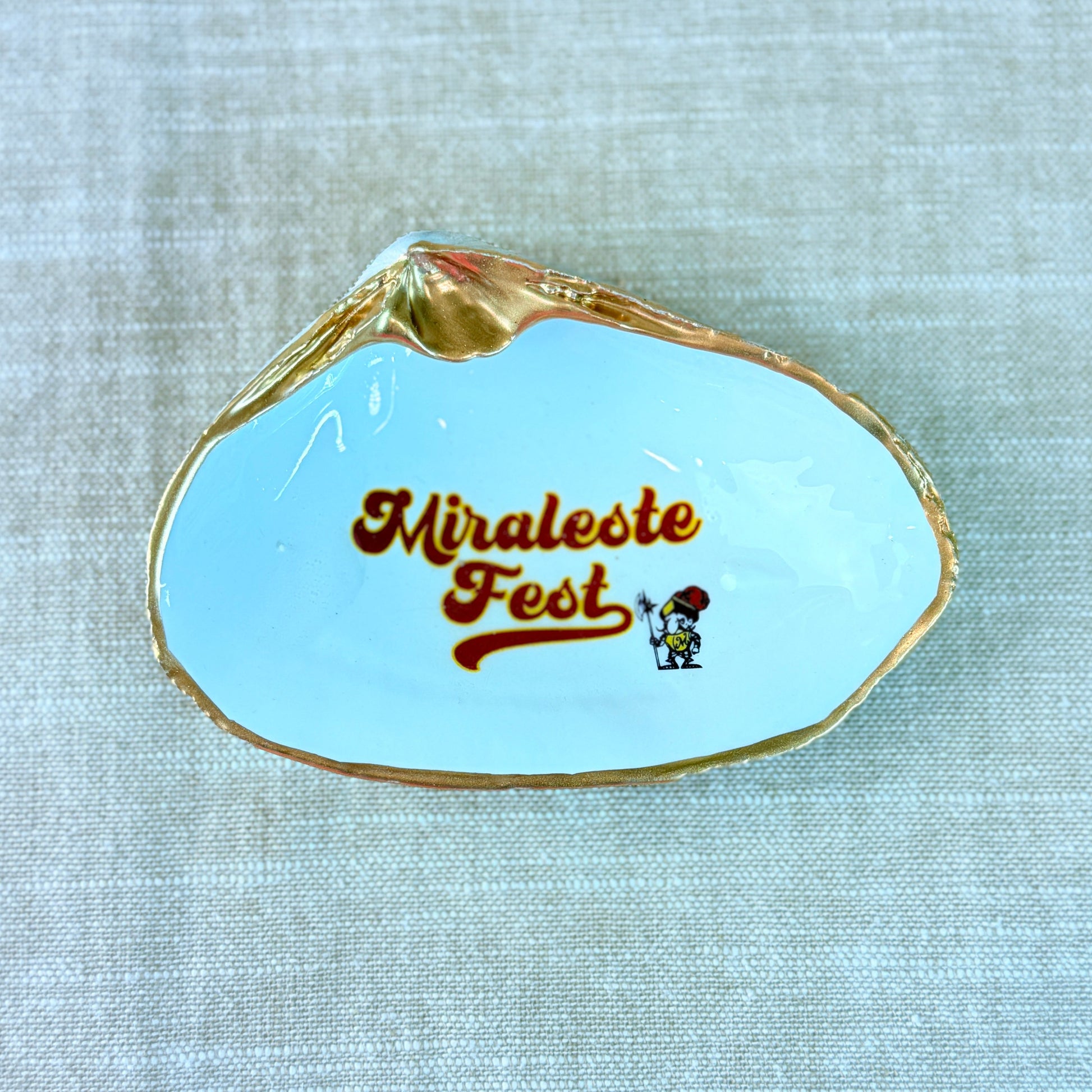 Shell-shaped dish with 'Miraleste Fest' text on a light beige background