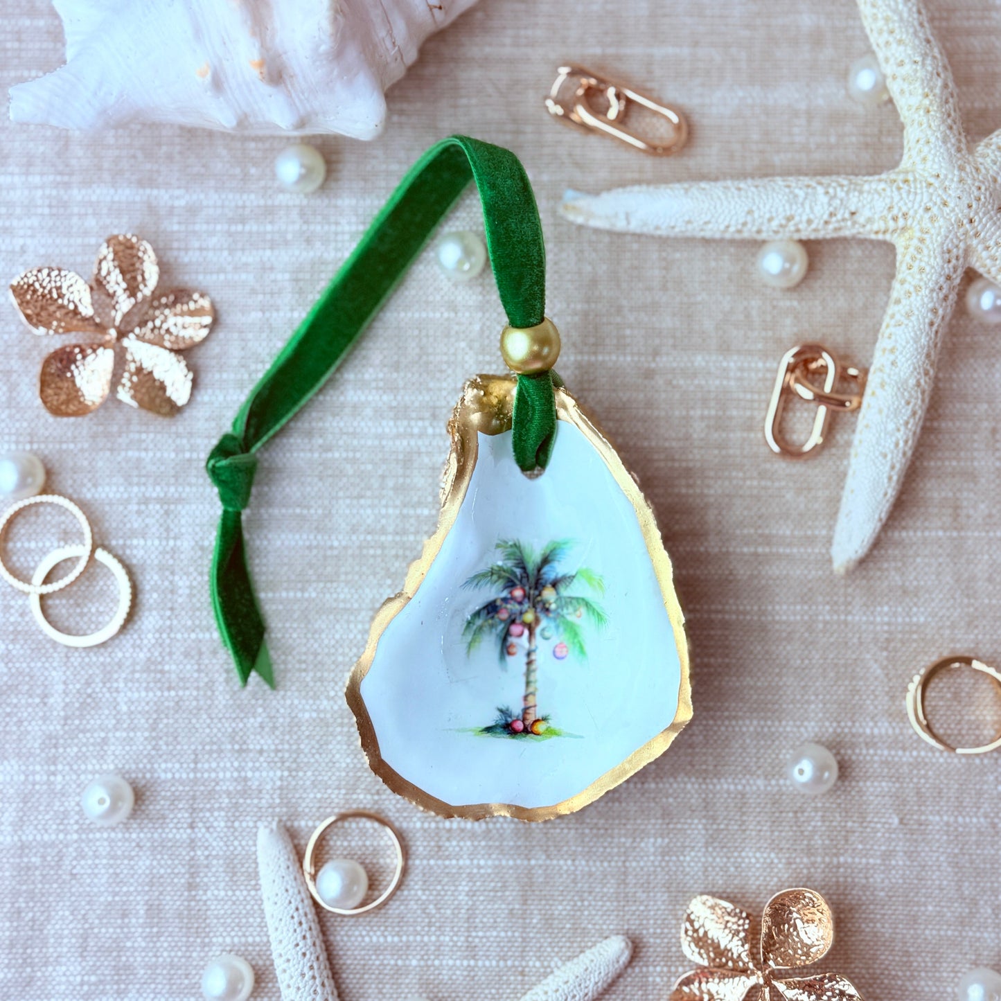 Decorative shell ornament with palm tree design on a textured surface with starfish and shells.